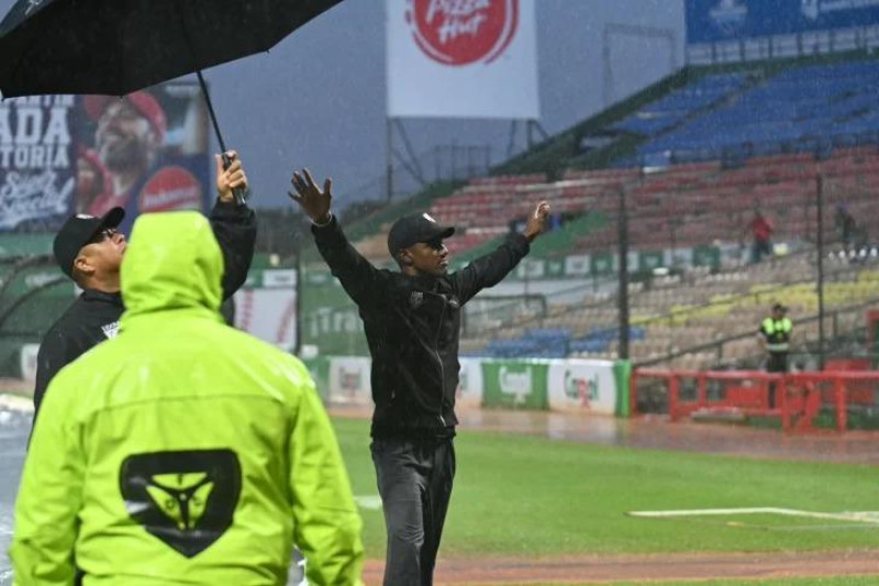 El árbitro principal, Yunior Torres, realiza la señal para indicar la suspensión del partido de este domingo entre Licey y Escogido.