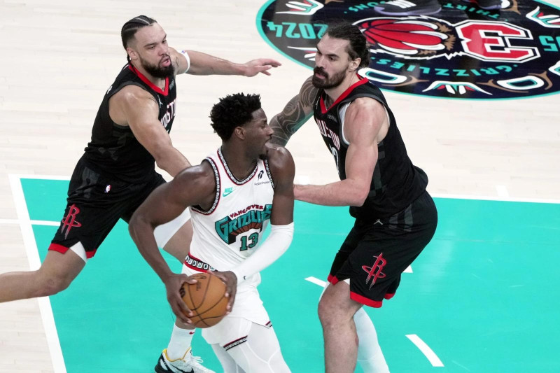 Jared Jackson Jr., de Memphis, realiza una gestión ofensiva frente a Steven Adams y Dillon Brooks, de los Rockets, en acción del baloncesto de la NBA.