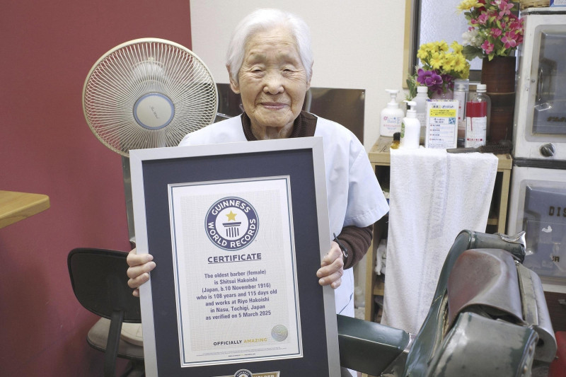 Shitsui Hakoishi, de 108 años, posa con el certificado de Guinness World Records que la reconoce como la barbera más anciana del mundo, en su barbería de Nakagawa, en la prefectura de Tochigi, en el este de Japón, el miércoles 5 de marzo de 2025. (Kyodo Photo vía AP)