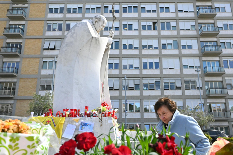 Una mujer camina junto a la estatua de Juan Pablo II afuera del Hospital Gemelli, donde está hospitalizado el Papa Francisco en Roma, el 11 de marzo de 2025.
