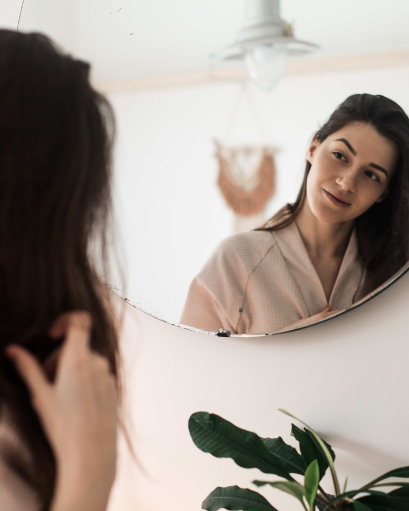 Una joven simula hablar sola frente a un espejo.