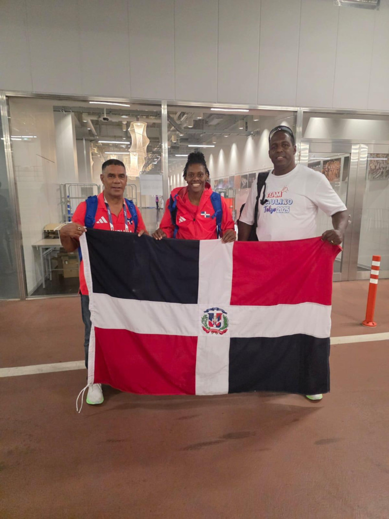El presidente de la Federación de Atletismo, Alexis Peguero con la bandera dominicana junto a Marileidy Paulino y su entrenador, Yassen Pérez, luego de la carrera final.