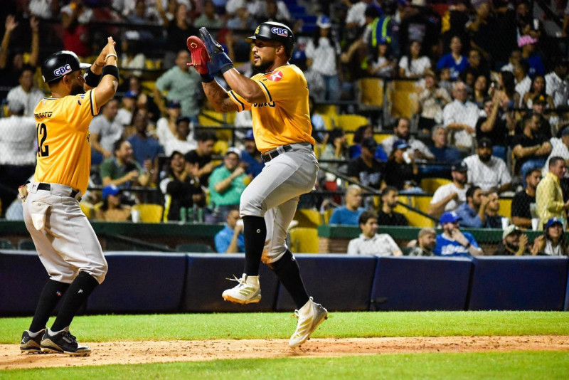 Dos jugadores de las Águilas celebran tras marcar una carrera en el juego contra Licey.