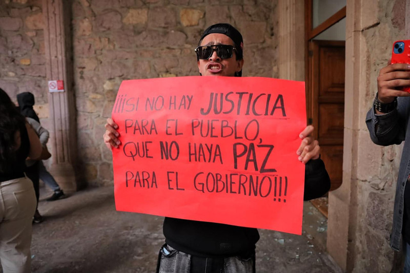 Una persona sostiene un cartel durante una manifestación este domingo, en el Palacio de Gobierno en Morelia (México). Cientos de mexicanos salieron a las calles de Morelia para exigir justicia por el asesinato del alcalde de Uruapan, Carlos Manzo Rodríguez, ocurrido la noche del 1 de noviembre tras un evento público. EFE/ Iván Villanueva