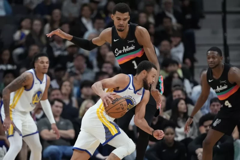 Stephen Curry, de los Warriors, conduce el balón frente a Victor Wembanyama, de los Spurs, durante la segunda mitad del partido de la NBA, el 12 de noviembre de 2025.