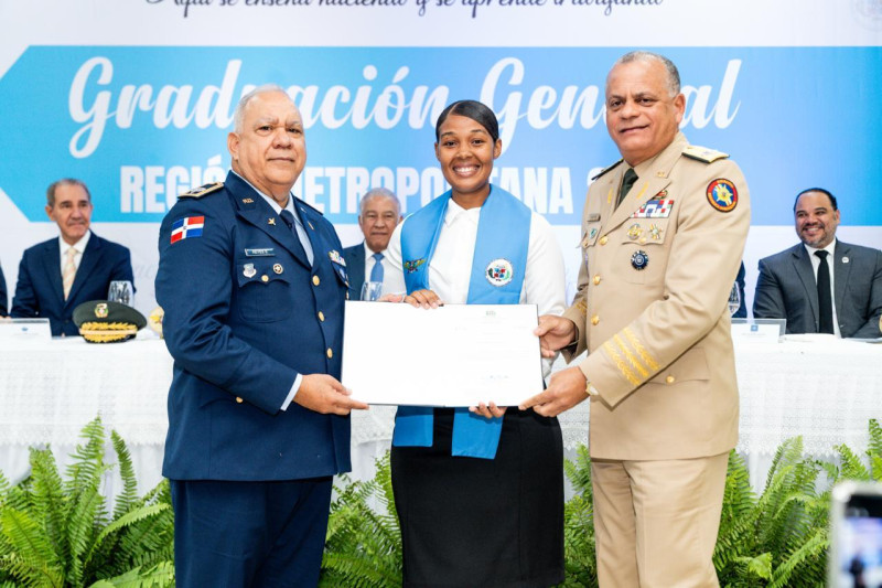 El ministro de Defensa, teniente general, Carlos Antonio Fernández Onofre, y el coronel José Reyes Suárez, entregan el título a una de los graduandos.
