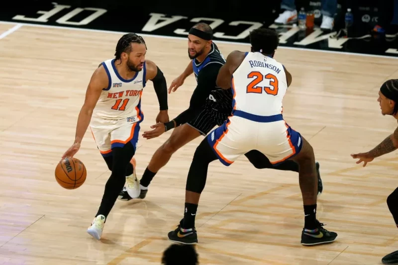 El base de los Knicks Jalen Brunson avanza con el balón frente a Jalen Suggs del Magic y su compañero Mitchell Robinson en el encuentro del 7 de diciembre del 2025.