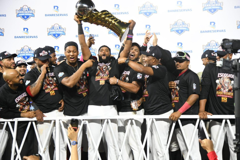 Sócrates Brito, acompañado de sus compañeros, levanta jubiloso el trofeo tras el triunfo del Escogido en el quinto partido de la serie final.