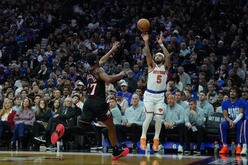 Jose Alvarado, de los Knicks, se alza para lanzar de larga distancia sobre Vj Edgecombe, de los Sixers, durante el juego de la NBA, el 11 de febrero de 2026, en Filadelfia.