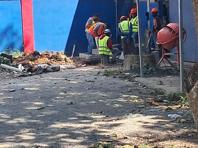 Varios obreros trabajan en una de las esquinas de una cancha abiertas de voleibol.