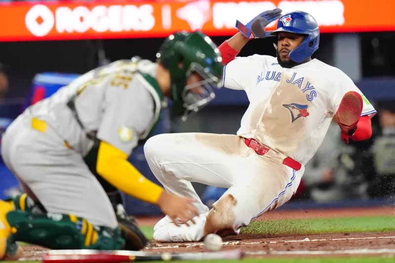 Vladimir Guerrero, de los Azulejos, se desliza para anotar ante el receptor Shea Langeliers en la sexta entrada del juego de MLB, el 28 de marzo de 2026.