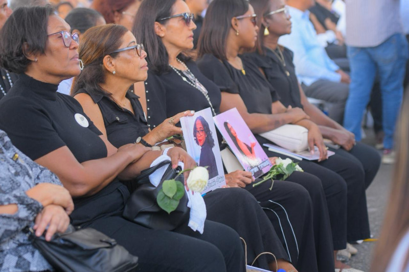 Familiares sostienen fotografías y flores blancas en memoria de sus seres queridos.
