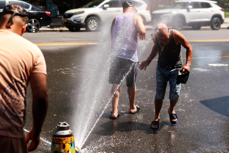 Hombres se refrescan ante ola de calor.
