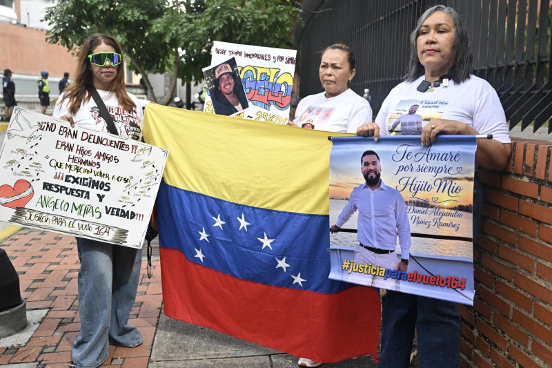 Tres mujeres, familiares de migrantes venezolanos, sostienen pancartas con fotos de sus familiares durante una protesta frente al edificio de la misión gubernamental Retorno a la Patria en Caracas, el 24 de agosto de 2026.
