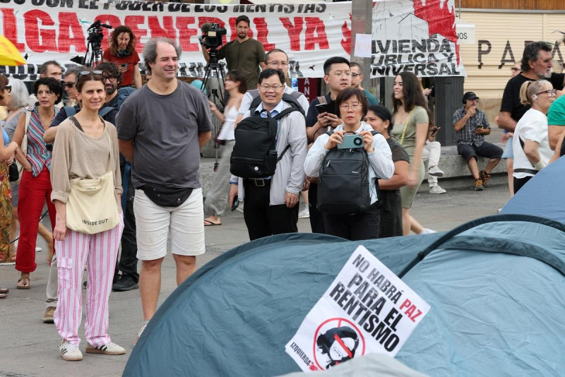 Turistas toman fotografías mientras manifestantes acampan en tiendas de campaña para protestar contra los desahucios y la crisis de la vivienda frente a la sede de la Presidencia, ayer en Madrid.