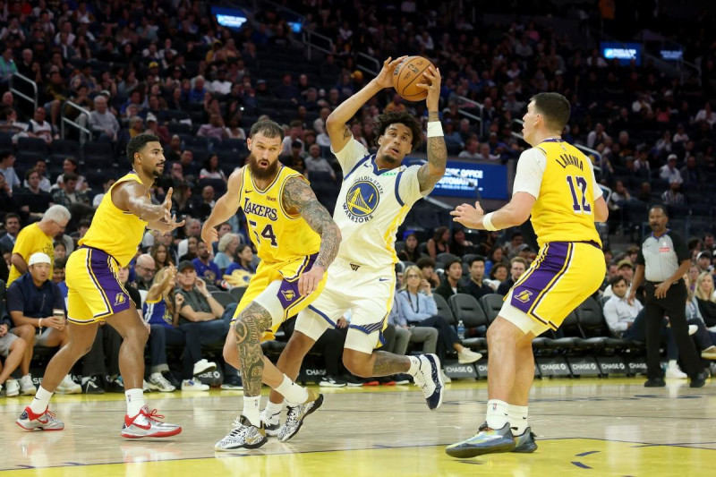 Yaxel Lendeborg, de los Warriors, protege el balón ante la defensa de Sandro Mamukelashvili y Jake LaRavia, de los Lakers, en la pretemporada de la NBA.