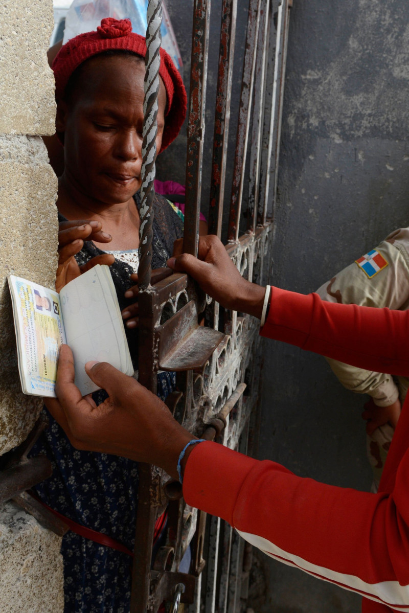 Tras una reja esta mujer espera la verificacio´n de su pasaporte para ingresar a suelo dominicano