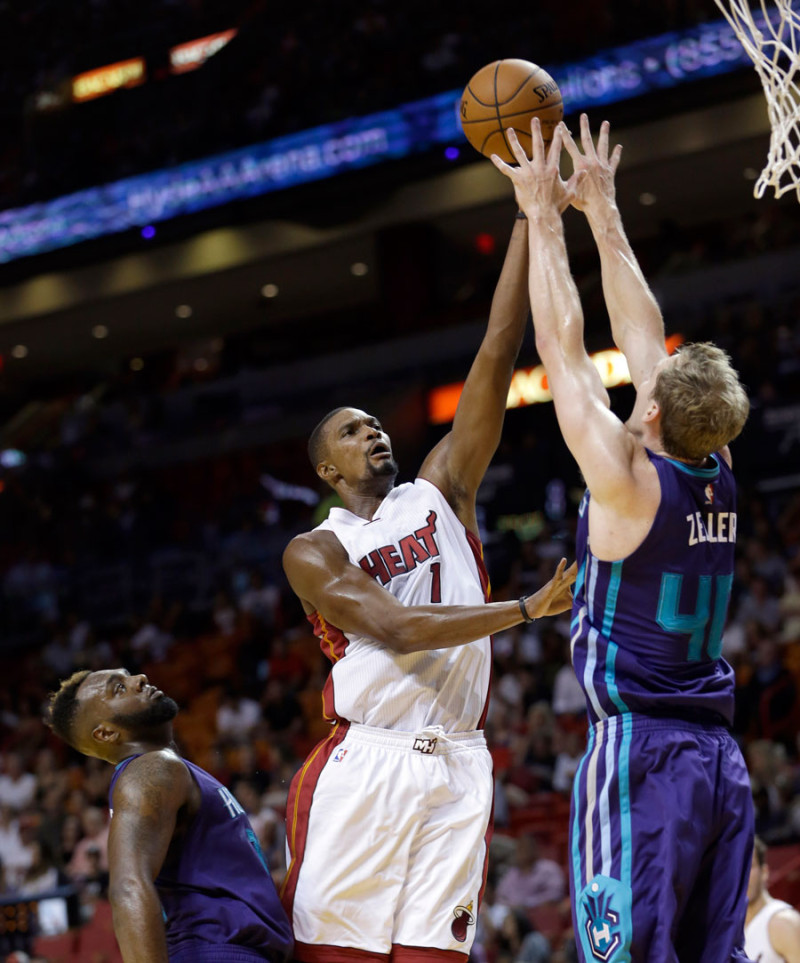 Chris Bosh, de los Heat de Miami, lanza sobre la defensa de Cody Zeller, de los Hornets de Charlotte, en la primera mitad del partido de pretemporada de la NBA.