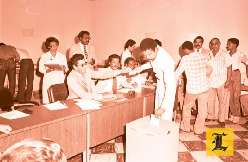 Mayo 1982. Ciudadanía. Un ciudadano deposita su voto en la urna frente a representantes de la mesa electoral.