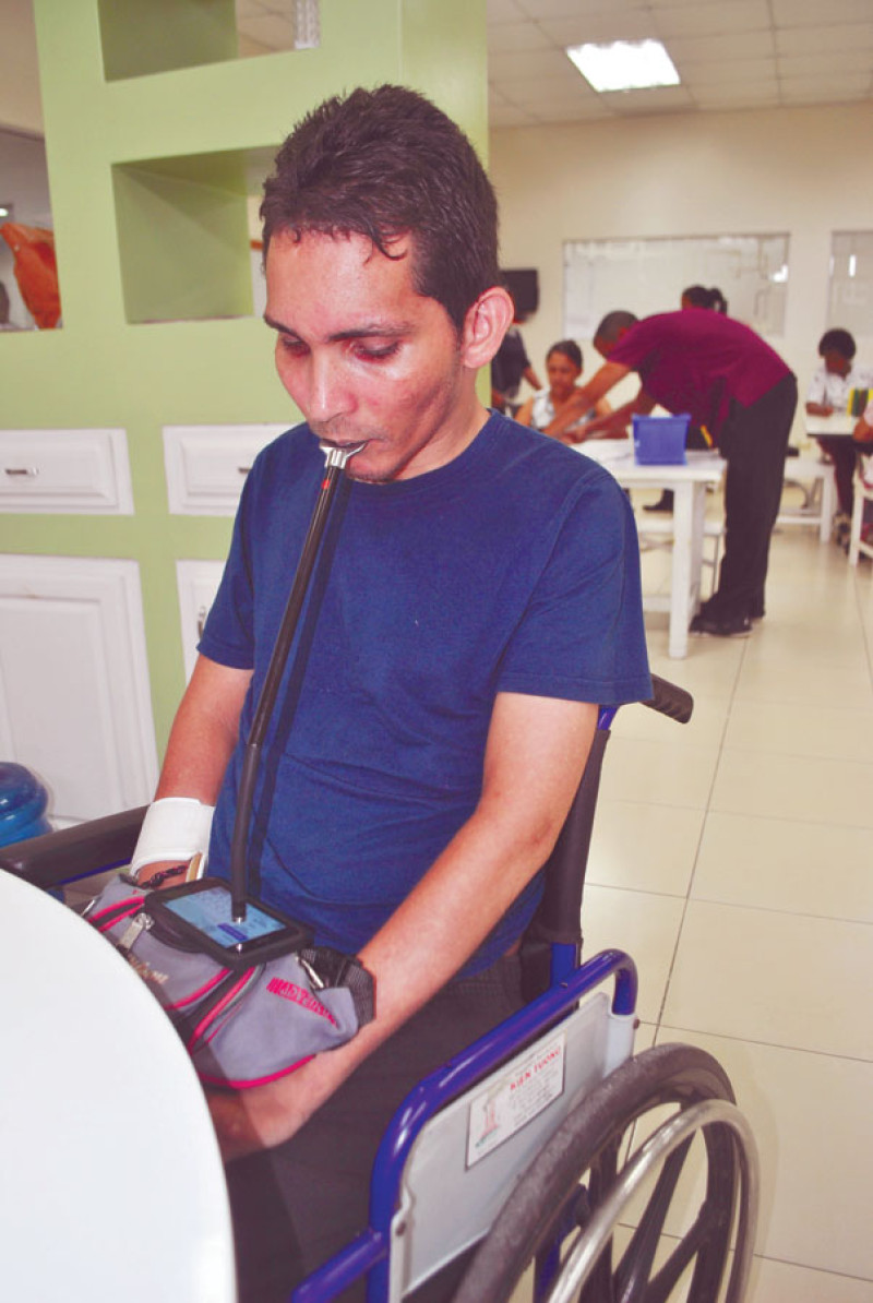 Comunicado. Aneuris García Falette, de 35 años, utiliza un “mouse stick” (lápiz digital) para chatear con su celular durante un momento de su jornada de terapias en la Asociación Dominicana de Rehabilitación.