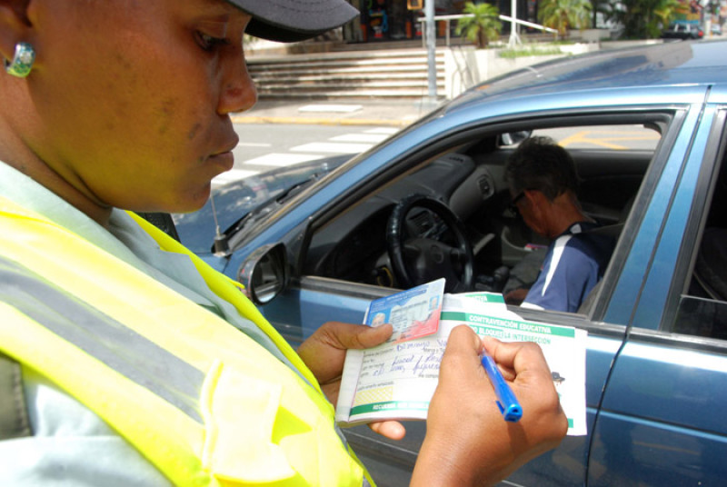 Operativo. Una agente de la Amet coloca una "multa moral" a un coductor que violó la ley de tránsito.
