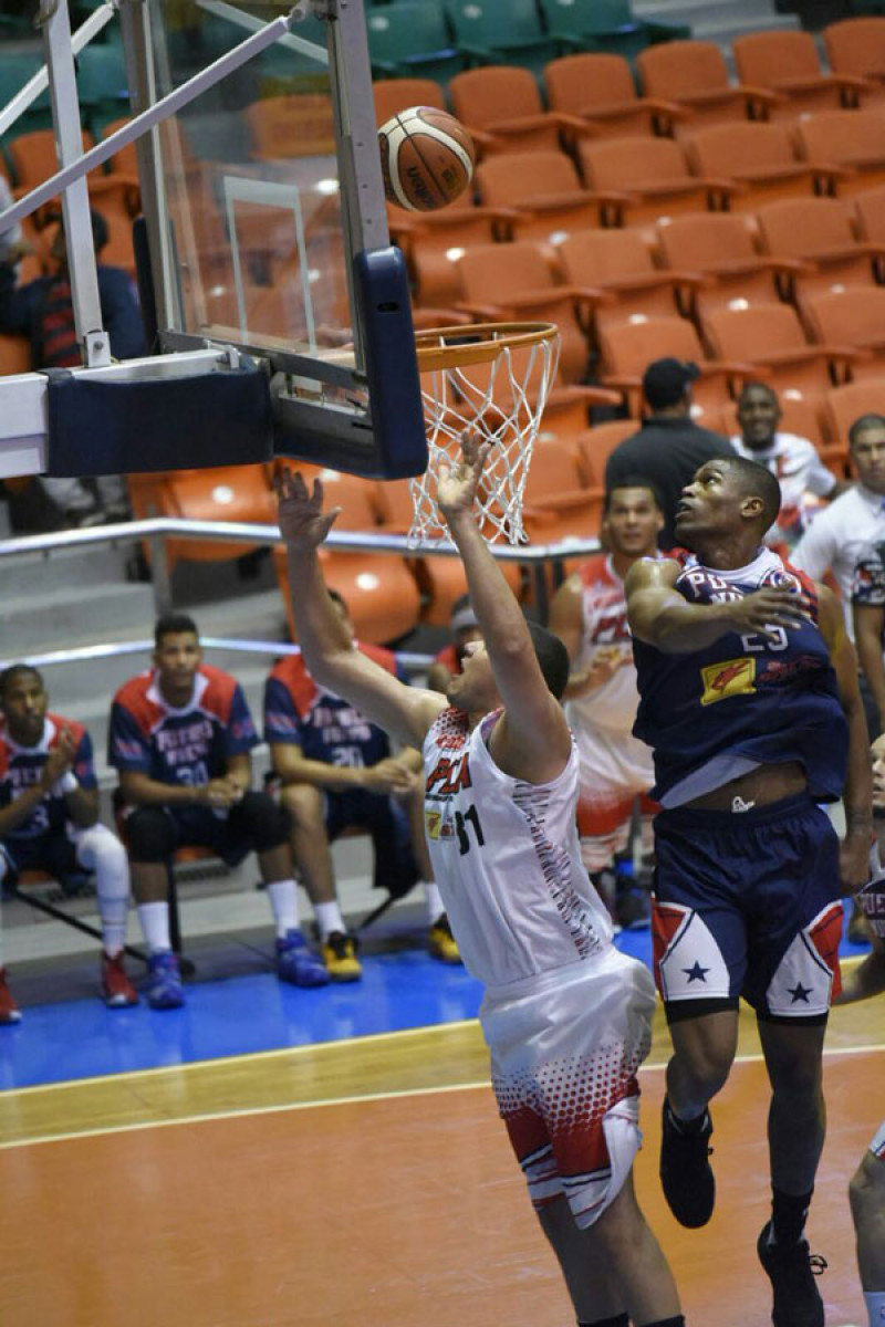 Charlie Rodríguez, de Plaza, disputa un balón con Antonio Peña, de Pueblo Nuevo, en el primero de dos partidos de la jornada dominical del torneo de baloncesto superior de Santiago.
