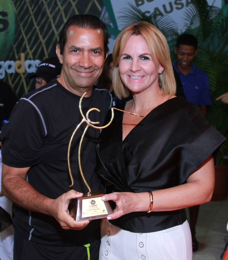 Gianni Paulino premia a Danilo Pérez, ganador de la categoría C-3 para mayores de 45 años del torneo de tenis benéfico “Manos Arrubadas”.