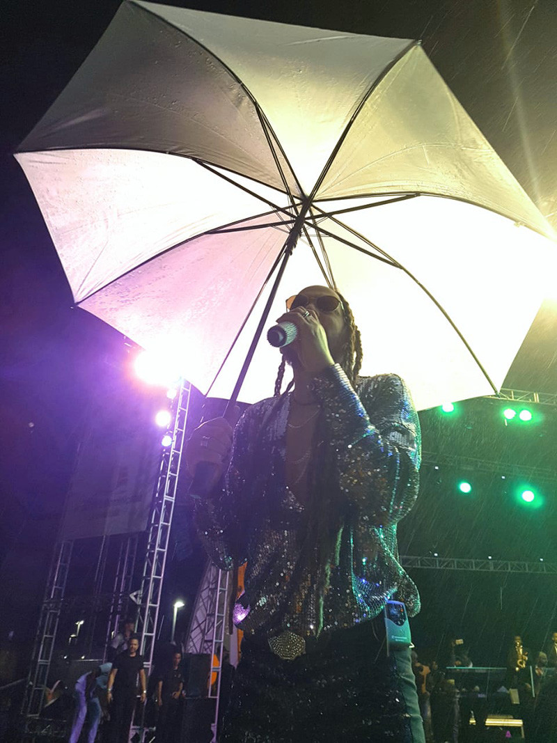 Toño Rosario tuvo que cantar bajo paraguas por la lluvia que no cesó en Puerto Plata la noche del sábado y la madrugada del domingo.