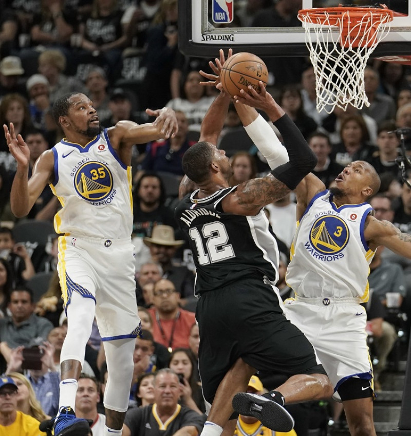 LaMarcus Aldridge, de los Spurs, intenta anotar un canasto ante la cerrada defensa de Kevn Durant y David West, de los Warriors, en el cuarto partido de la serie de playoffs de la NBA.