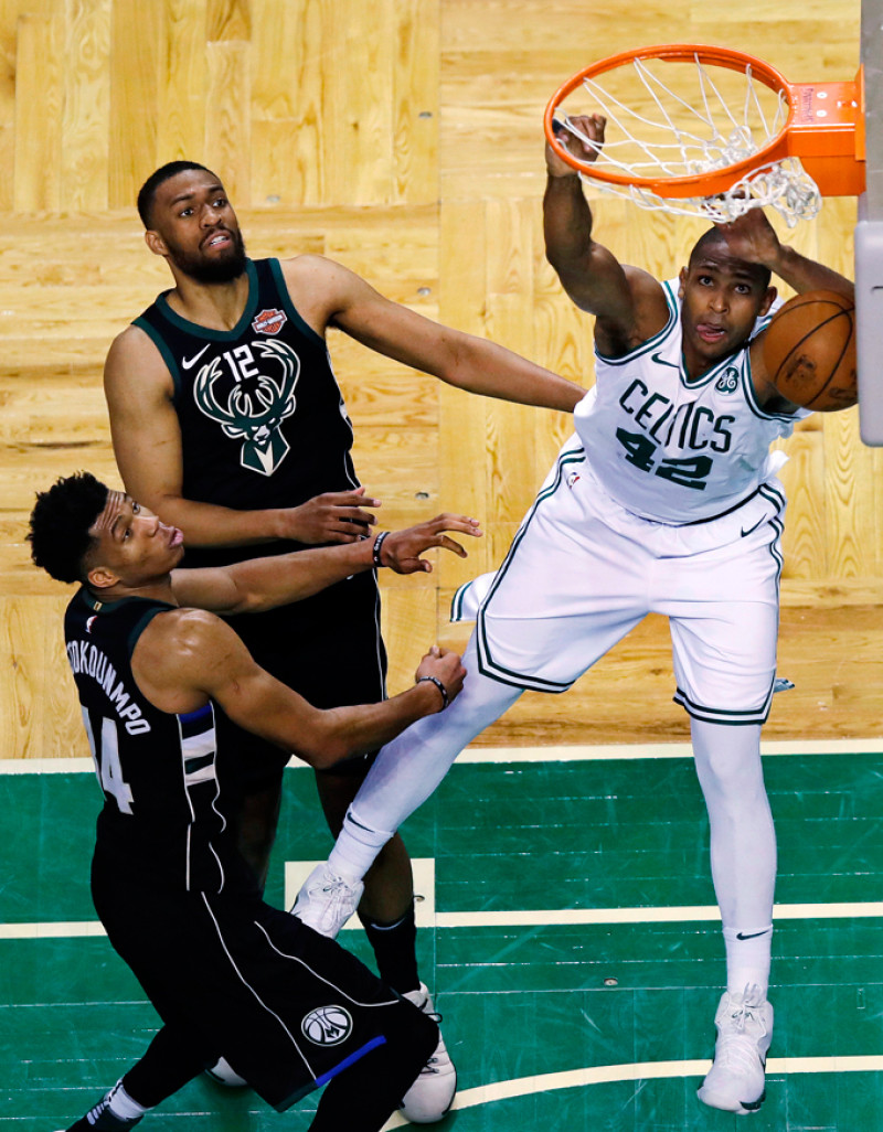 Al Horford, de los Celtics, encesta un canasto ante la mirada de Jabari Parker y Giannis Antetokounmpo, de Milwaukee, en acción del partido de anoche en los playoffs de la NBA.