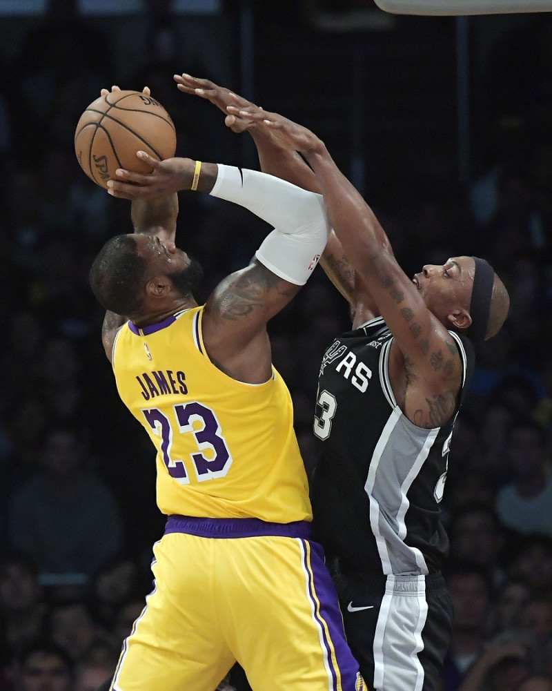El astro de los Lakers de Los Angeles, LeBron James, dispara ante la defensa de Dave Cunninghan, de los Spurs de San Antonio.