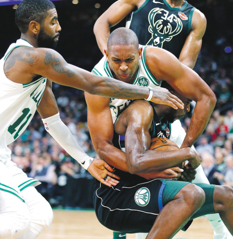 El dominicano Al Horford disputa con fiereza el balón con Kris Middleton en la acción del partido de anoche que ganaron los Celtics a los Bucks. Kyrie Irving observa la jugada.