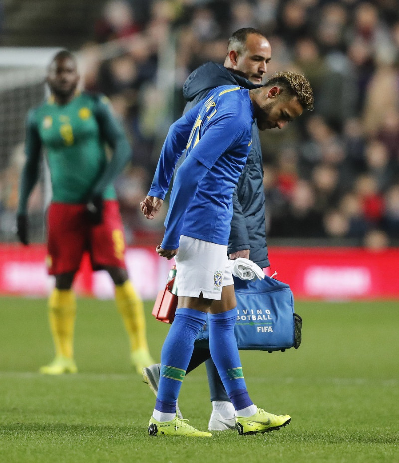 Neymar mientras abandonaba el campo en compañía del preparador físico de Brasil  en medio del partido contra Cameroon.