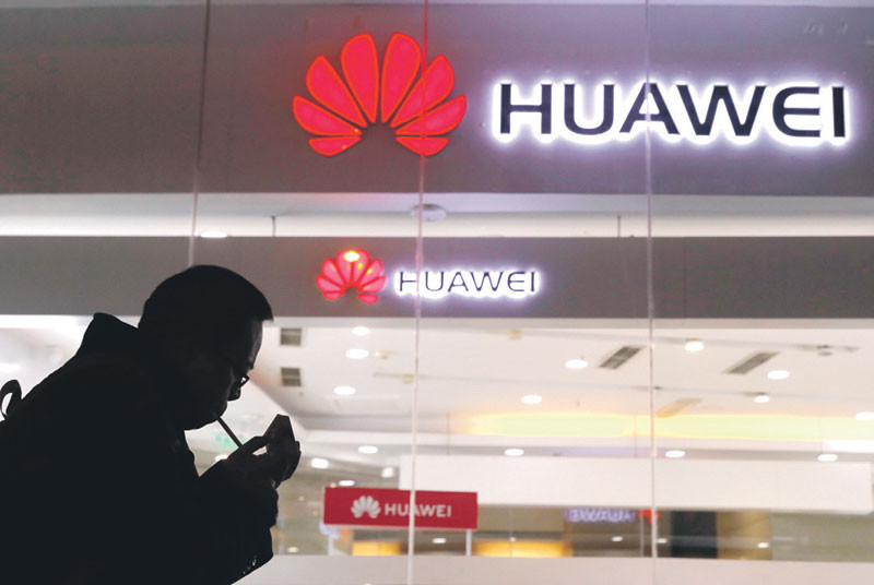 Logo. Un hombre enciende un cigarrillo afuera de una tienda Huawei en Pekín, el jueves pasado.