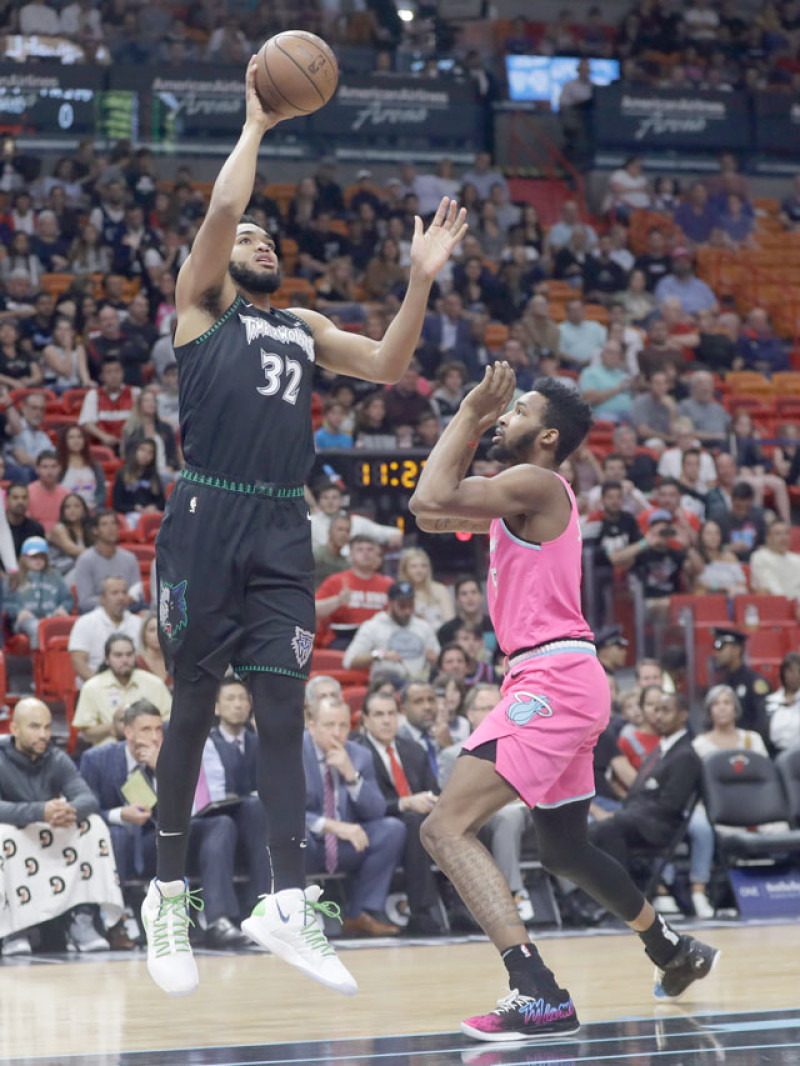 Karl-Anthony Towns, de Minnesota, realiza un intento al cansto sobre Derrick Jones Jr. de Miami, en acción de la primera mitad del partido de ayer en la NBA.