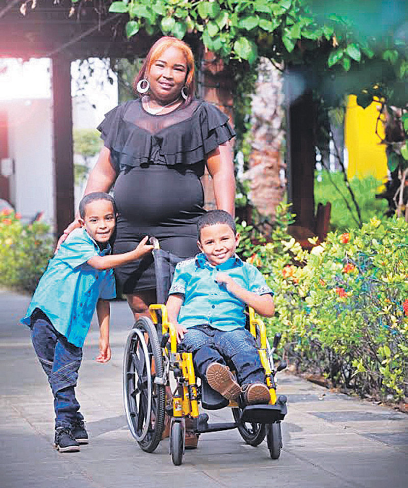 Marilanda Mora, junto a sus dos pequeños. David, mostrado aquí sentado en silla de ruedas, recibe terapias en el CAID para mejorar su condición.
