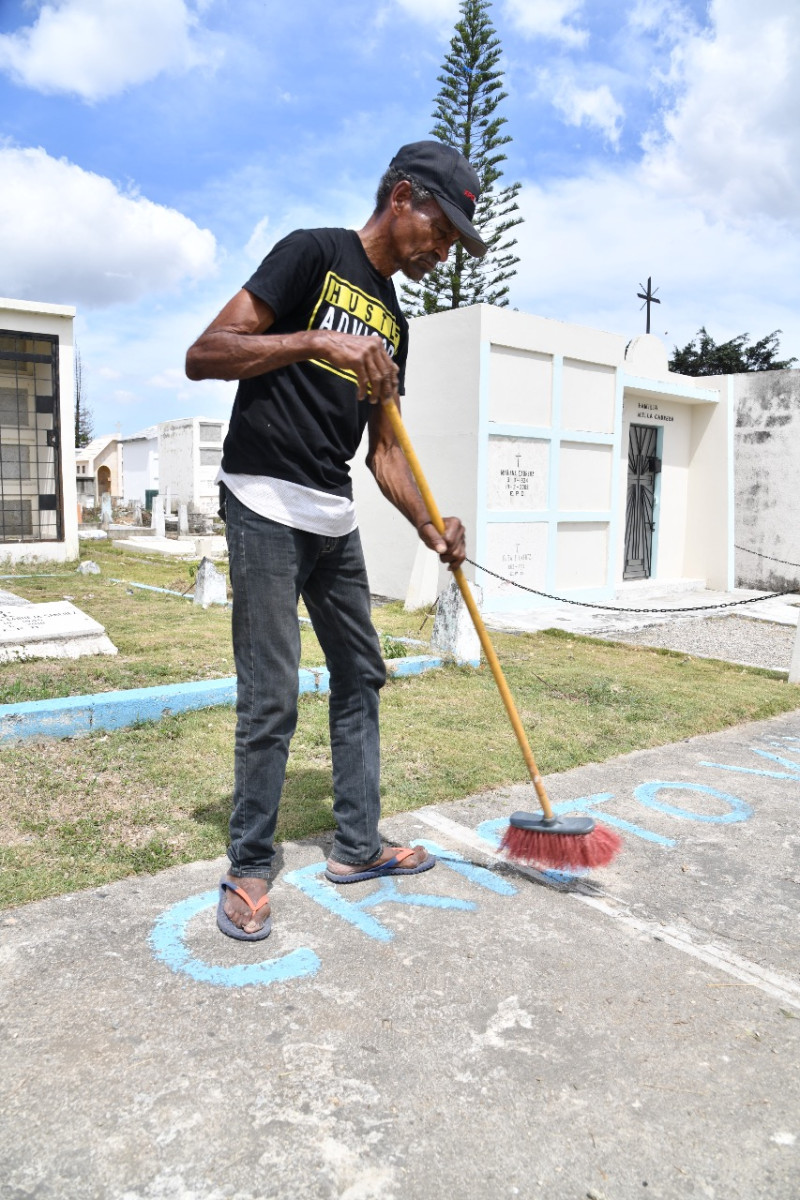 Un hombre limpia tumba en el cementerio. Foto: Víctor Ramírez