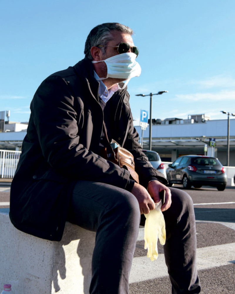 Un pasajero con una máscara protectora, en medio de las preocupaciones sobre el brote de Covid-19, espera afuera de la terminal de salida en el aeropuerto de Milán./AFP