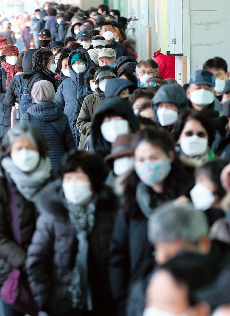 Las personas con mascarillas hacen fila para comprar cubrebocas frente a un supermercado en Seúl. / AFP