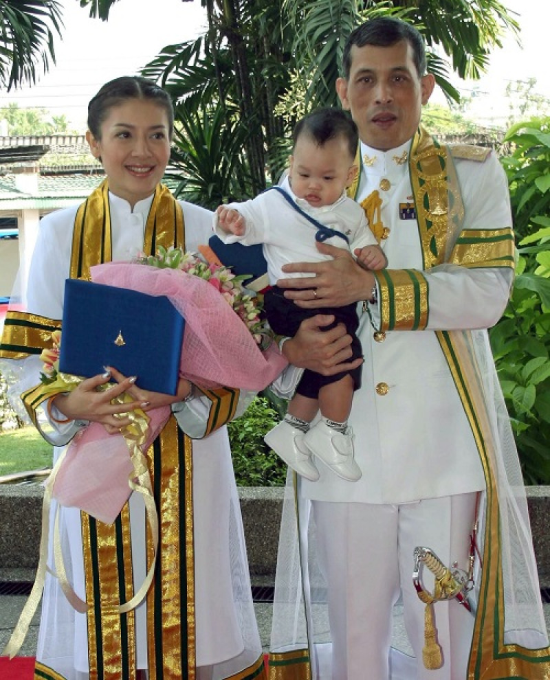 El príncipe heredero Maha Vajiralongkorn sostiene en brazos a su hijo, el pequeño príncipe Dhipankara Rasmijoti, mientras su entonces ,esposa la princesa Srirasmi les mira.