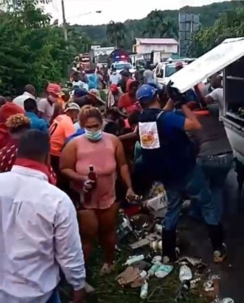 Se observan personas tomando botellas de ron del camión accidentado en Puerto Plata que transportaba el licor.