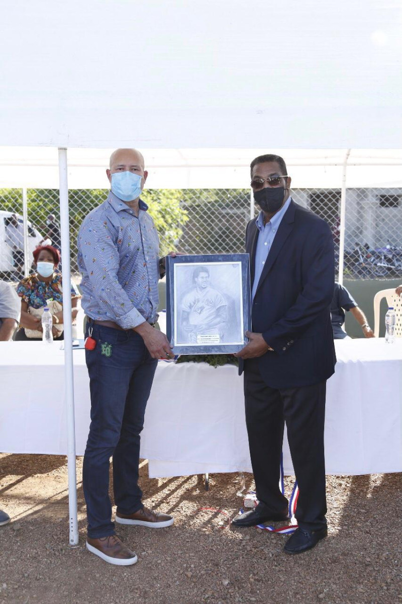 Manny Acta entrega una placa de reconocimiento a George Bell durante la inauguración del estadio de Pequeñas Ligas en Santa Fe.