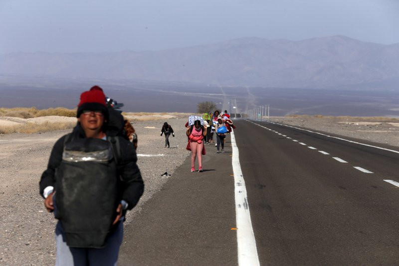 Migrantes, la mayoría de Venezuela, caminan junto a la carretera después de cruzar a Chile desde la frontera con Bolivia cerca de Colchane, Chile, el sábado 6 de febrero de 2021. (AP Foto/Luis Hidalgo