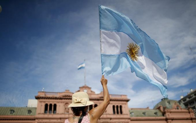 Una manifestante ondea una bandera de Argentina delante de la Casa Rosada durante una protesta contra el presidente del país, Alberto Fernández, y su gestión de las vacunas contra el COVID-19, en Buenos Aires, Argentina, el 27 de febrero de 2021. (AP Foto/Natacha Pisarenko)