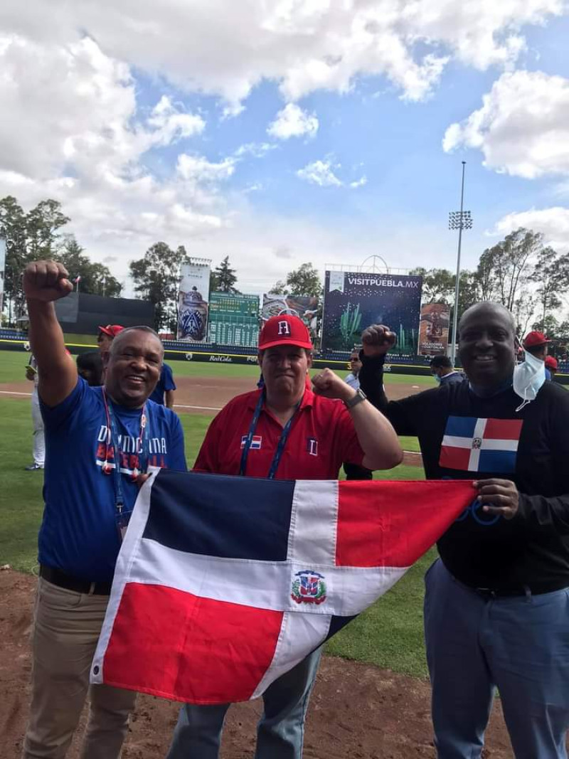 El empresario Felipe Vicini, presidente de Probeisbol sostiene la bamdera tricolor, junto a Juan Núñez, presidente de la Federación Dominicana de Béisbol y Gerardo Suero Correa, jefe de misión de la representación Dominicana.
