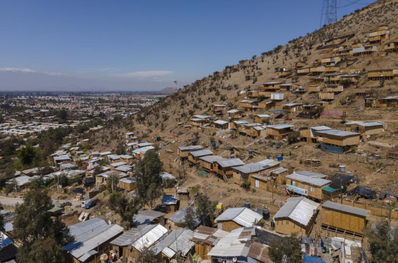 Las casas se encuentran en la ladera de una colina en un área sin pavimentar llamada "Bosque Hermoso", donde migrantes de Haití, Perú y Colombia se establecieron en Lampa, Chile, el viernes 1 de octubre de 2021. (AP Foto/Esteban Felix)