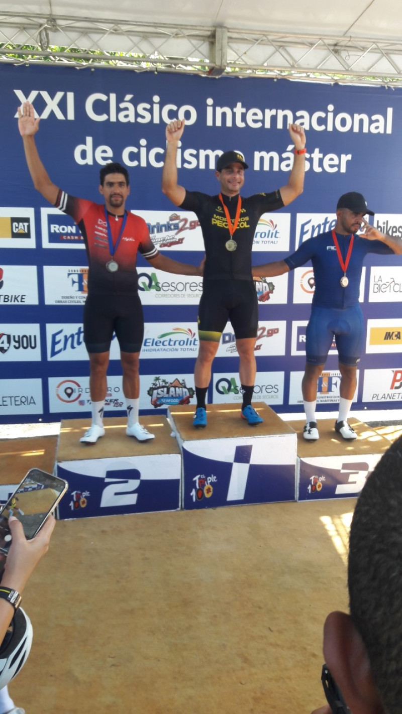 Juan Coronado figura en el podium de ganadores tras conquistar en Master A la tercera etapa del Clásico Triple 100 de Ciclismo. A sus lados figuran Nortlon Sánchez y Ramón Adames.