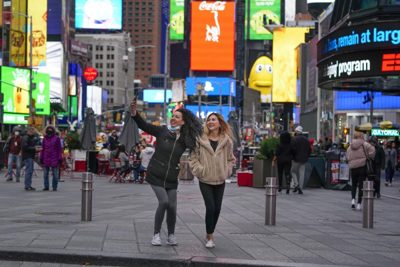 Los peatones posan para fotografías en Times Square, el lunes 15 de noviembre de 2021, en Nueva York. Incluso cuando los visitantes se apiñan nuevamente debajo de las pantallas gigantes en Times Square de Nueva York, las tiendas de souvenirs, restaurantes, hoteles y empresarios dentro del emblemático hito de EE. UU. Todavía se están recuperando de una asombrosa pandemia. (Foto AP / Seth Wenig)