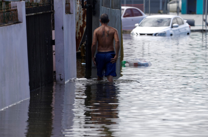 Un hombre camina por una calle inundada debido a las intensas lluvias registradas el pasado fin de semana, hoy, en Cataño (Puerto Rico). EFE/ Thais LLorca