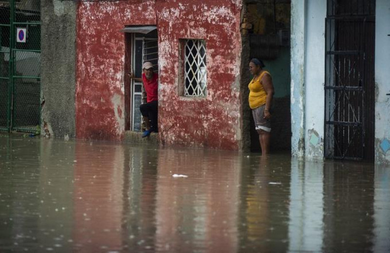 Personas miran una calle inundada desde una casa de La Habana, el 3 de junio de 2022. Los remanentes del huracán Agatha provocan este viernes intensas y persistentes lluvias en las provincias occidentales y centrales de Cuba.
YAMIL LAGE / AFP